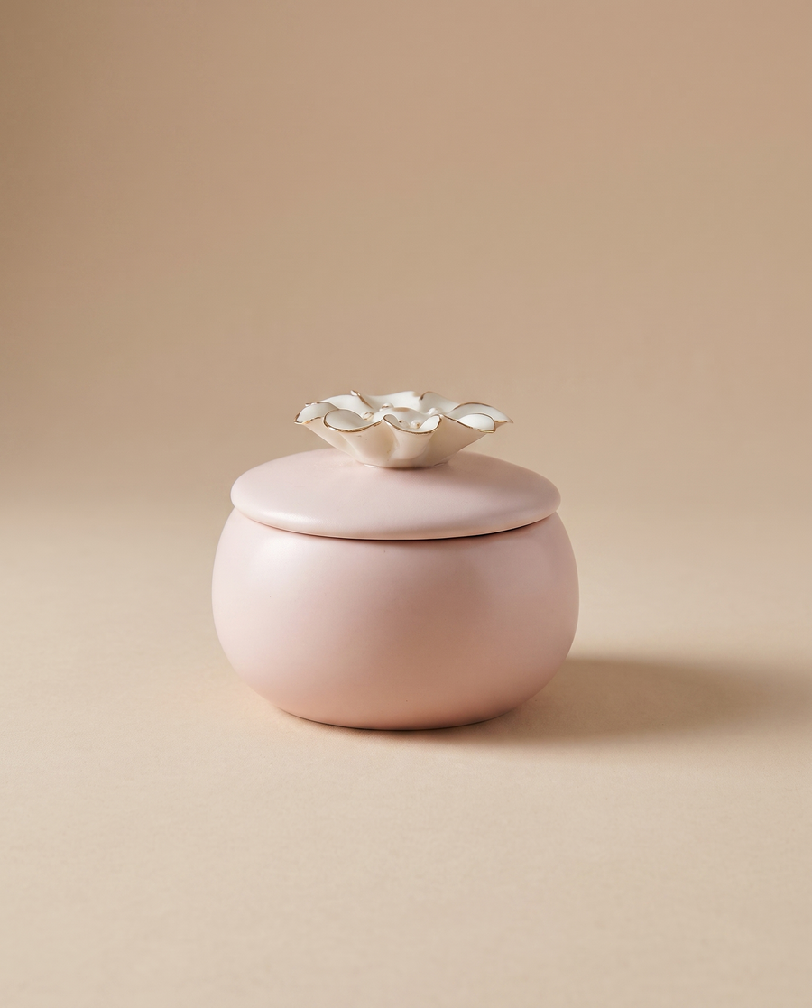 Quiet Hours blush-pink ceramic candle with a gold-trimmed flower lid, styled on a warm neutral background - Soft Existence