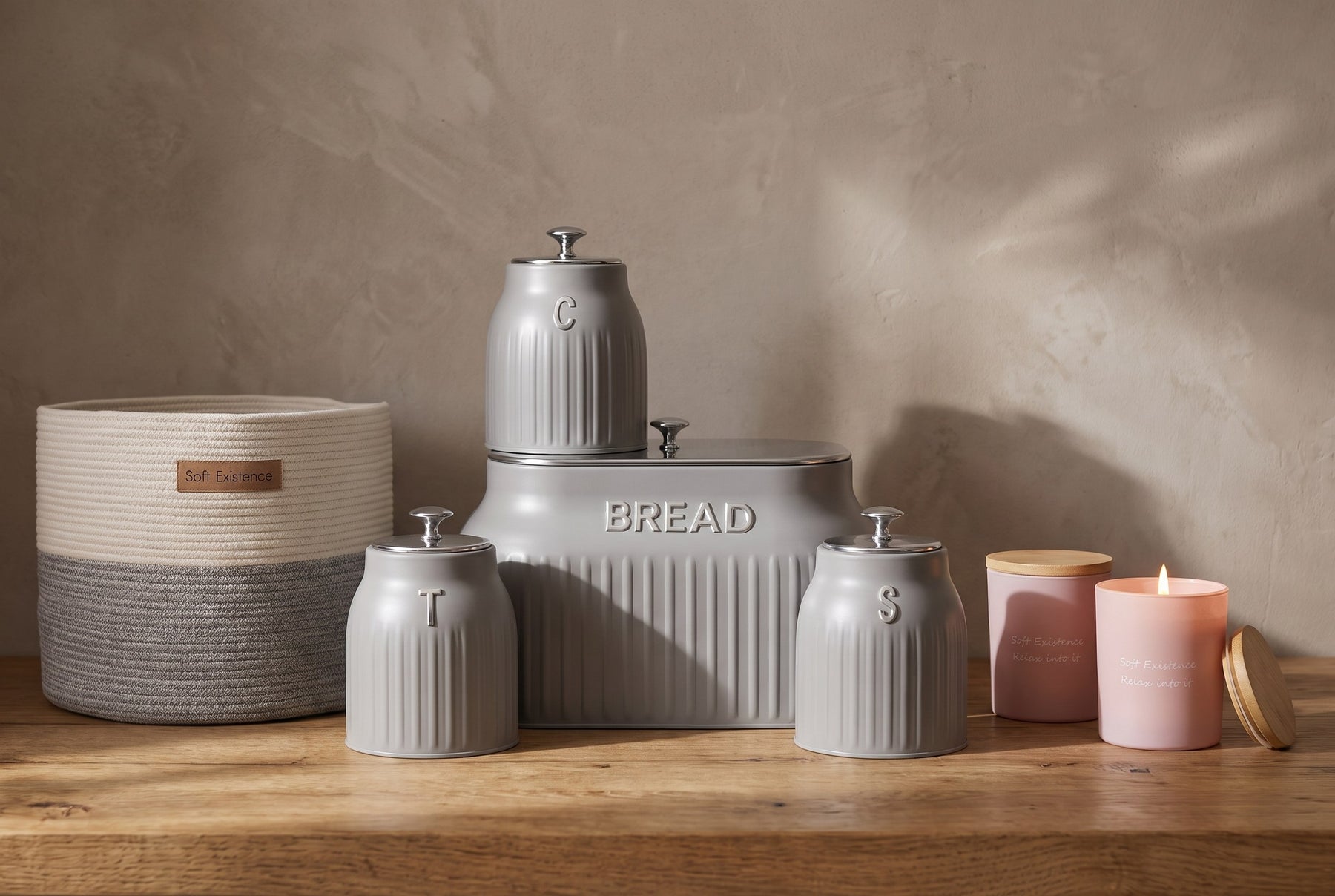 Grey ribbed kitchen storage set with a woven basket and candles on a warm wooden counter